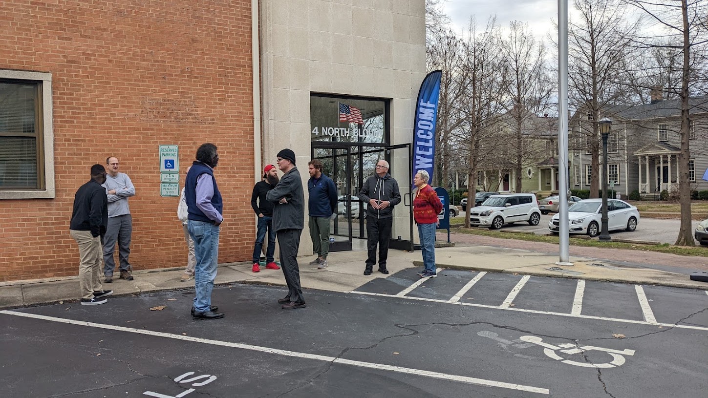 Outside of the raleigh campus of St. John's MCC a group of members are standing in the parking lot talking with each other